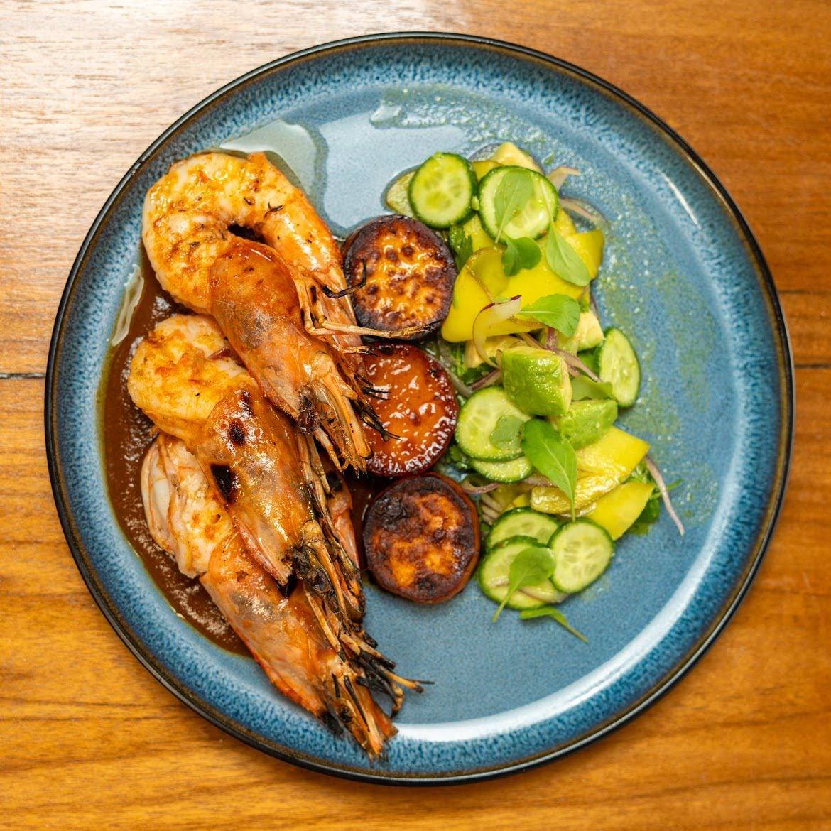 Langostinos a la parrilla con plátano maduro caramelizado y ensalada de pepino, aguacate y fruta tropical