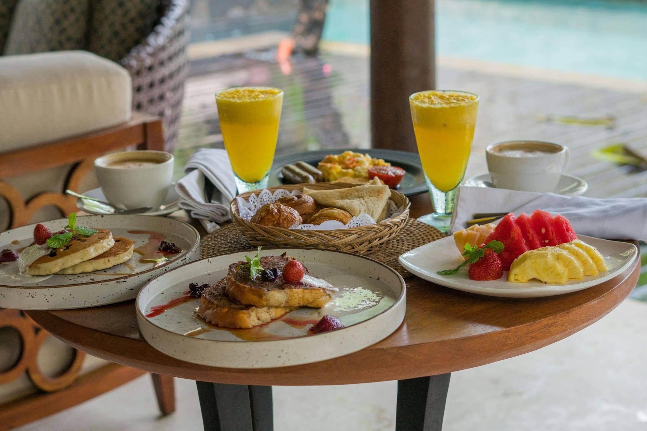 Desayuno servido con jugo, café y fruta junto a la piscina